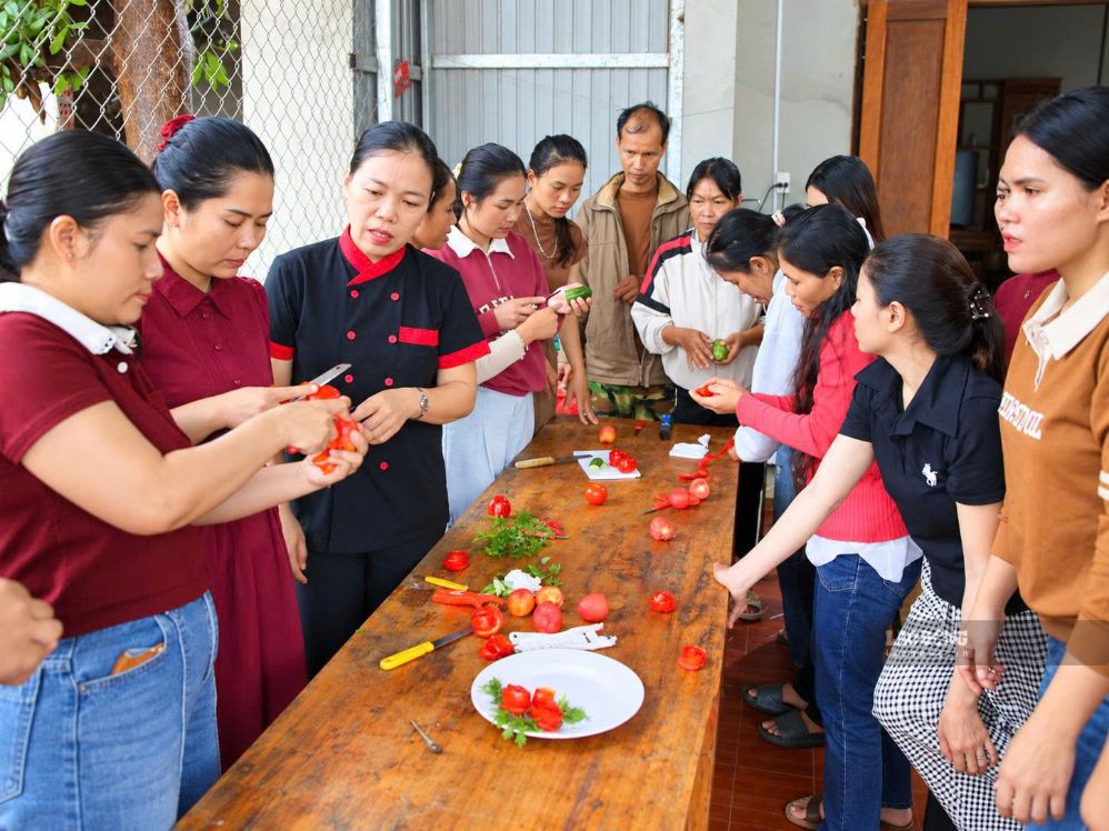 Cô giáo Nguyễn Thị Luận (thứ 3 từ trái sang) hướng dẫn các học viên người Pa Cô kỹ thuật cắt tỉa, trang trí rau củ tại lớp dạy nấu ăn ở thôn A Ngo (ảnh chụp tháng 9.2026). Ảnh: Hưng Thơ