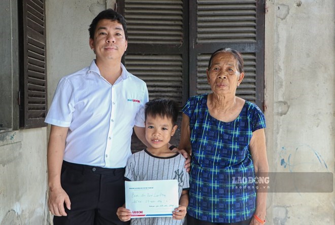 El reportero del periódico Lao Dong, en nombre de los lectores y el Fondo Social de Caridad Tam Long Vang - Periódico Lao Dong, entrega la cantidad de dinero de apoyo a Quy Duong. Foto: Nguyen Luan