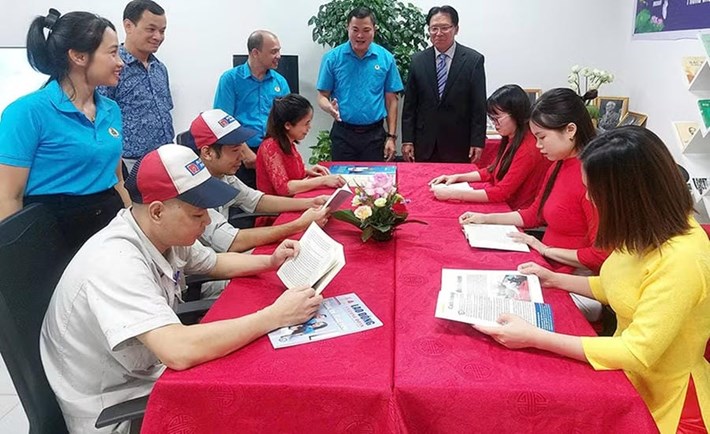 Trabajadores leyendo periódicos y revistas durante el descanso en el Punto de Actividades Culturales de Trabajadores de Nippon Paint Vietnam Co., Ltd. (Hanoi). Foto: Ngoc Anh