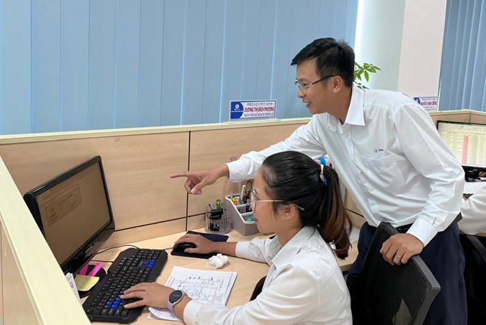 Thới Minh Nghiệp đang hướng dẫn đồng nghiệp sử dụng phần mềm trong ngành điện. Ảnh: Nhân vật cung cấp