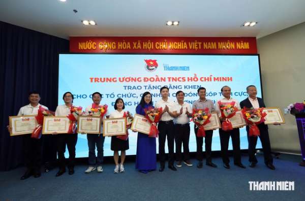 Anh Nguyễn Minh Triết cùng nhà báo Nguyễn Ngọc Toàn - Tổng biên tập Báo Thanh Niên trao bằng khen và hoa chúc mừng cho các cá nhân, đơn vị