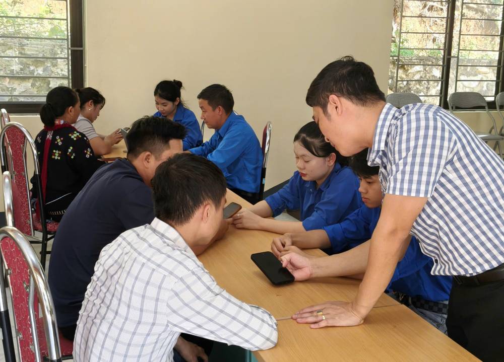Bí thư Đoàn Văn Trường (áo kẻ) hướng dẫn đồng bào sử dụng công nghệ số. Ảnh: Thu Hạnh
