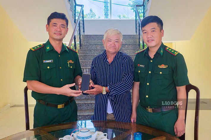 Trung tá Bùi Ngọc Thiệp (bên trái), Bí thư Đảng ủy, Chính trị viên Đồn Biên phòng Cửa khẩu quốc tế Bình Hiệp và Thượng úy Đặng Hoàng Kha (bên phải), Đội trưởng Đội Trinh sát trao trả điện thoại cho người nhà ông Nguyễn Thành Nghĩa. Ảnh: Minh Quân