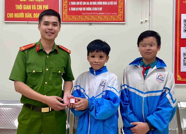 Hai em học sinh mang chiếc nhẫn bạc nhặt được giao nộp công an xã Đam Rông 3. Ảnh: Công an xã Đam Rông 3