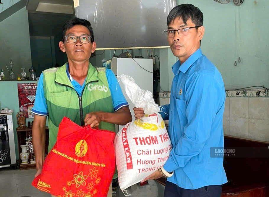 Ông Lê Tấn Lưu - Chủ tịch Nghiệp đoàn xe ôm công nghệ Bình Tân (bên phải) tặng quà cho nghiệp đoàn viên có hoàn cảnh khó khăn. Ảnh: Đức Long