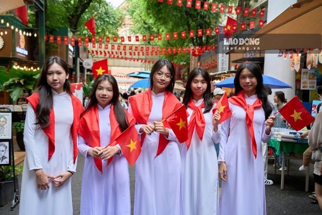 人们身着奥黛,手持旗帜在胡志明市中心打卡,庆祝9月2日国庆节。照片:英图
